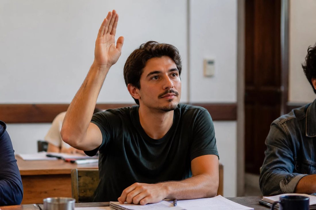 Facilitador de pé apontando para um argumento escrito no quadro durante a sessão
